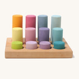Different sized wooden Grimms pastel rollers in a wooden frame on a cream background.