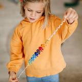 An toddler holding each end of the giant Grimms spirelli available at Babipur with the coloured disks threading through the metal wire