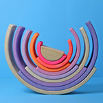 Grimm's 10-Piece Rainbow - Neon Pink- on a plain blue background. Front view of an alternative layout for the puzzle.