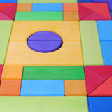 A close up of the Grimm's Basic Building Set 2 wooden block set. The photo shows the varying natural wood grain markings showing through the colourful natural dyes on the wooden blocks.