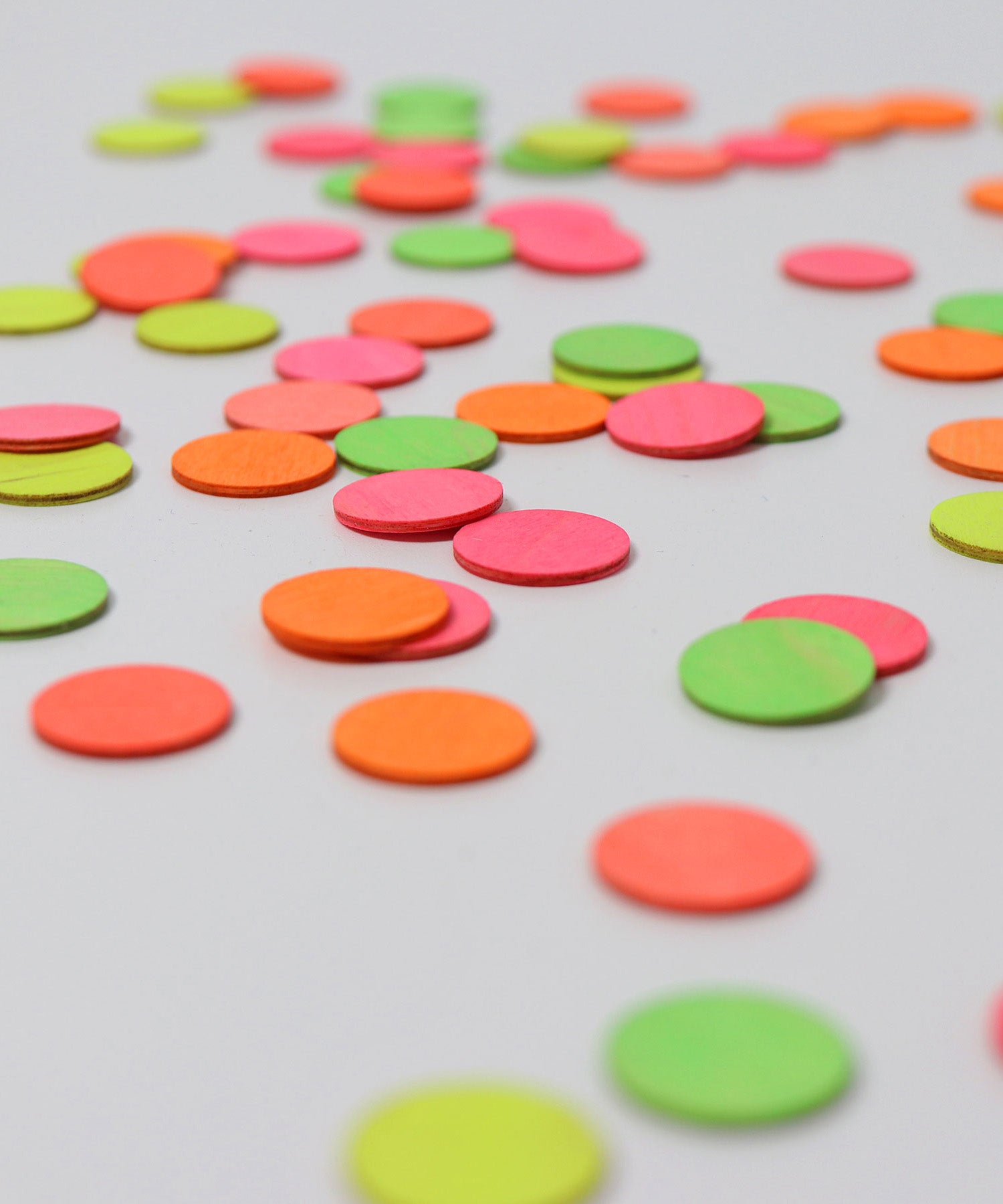 A close up of the Grimms wooden confetti dots. Showing the hand painted neon finish