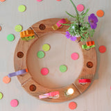 Grimm's Neon Celebration Confetti Dots. The dots surround a celebration ring on a wooden table.