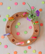 Grimm's Neon Celebration Confetti Dots. The dots surround a celebration ring on a wooden table.