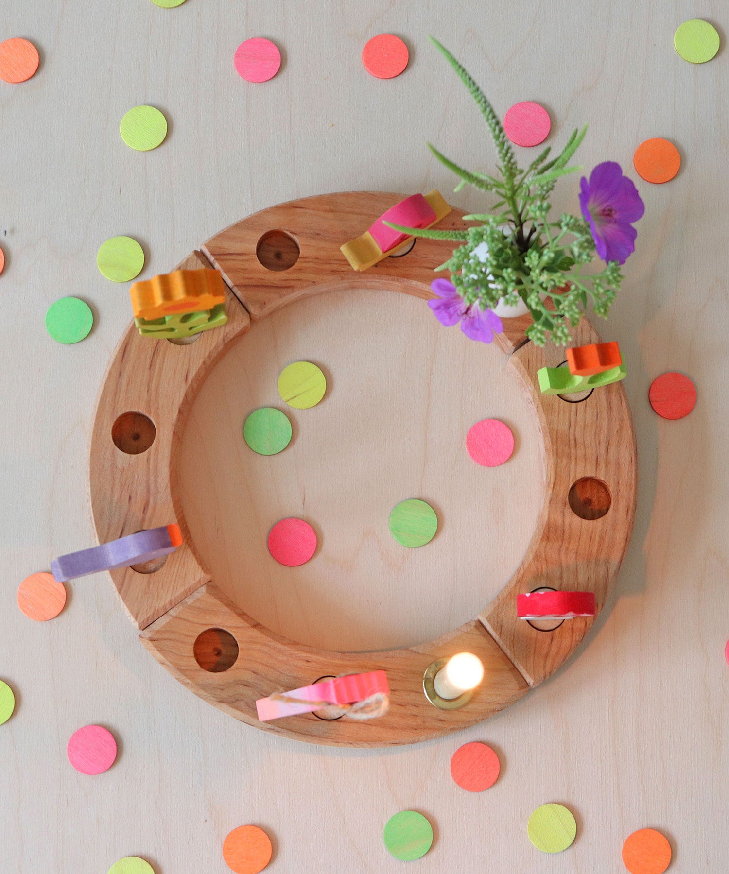 Grimm's Neon Celebration Confetti Dots. The dots surround a celebration ring on a wooden table.