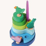 A Grimms decorative blue wooden stand with 3 different birds and a purple candle in a brass candle holder slotted in the stand.