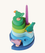 A Grimms decorative blue wooden stand with 3 different birds and a purple candle in a brass candle holder slotted in the stand.