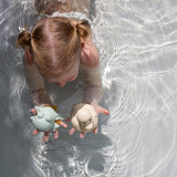 Hevea Upcycled rubber sand duck and sage frog toys being played in the pool by a small child