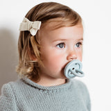 Close up of young child with a Hevea natural rubber pacifier in her mouth