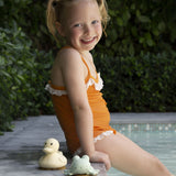 Hevea Upcycled rubber sand duck and sage frog toys on the poolside next to a small child