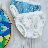 A child happily playing outside wearing a white top and the Imse Blue spotty Training Pants from the Blue/Teddy Training Pants Junior Set