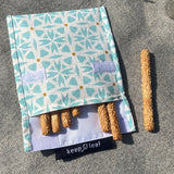 A close up of the organic cotton geo Keep Leaf large baggie outside on a blanket opened with food inside