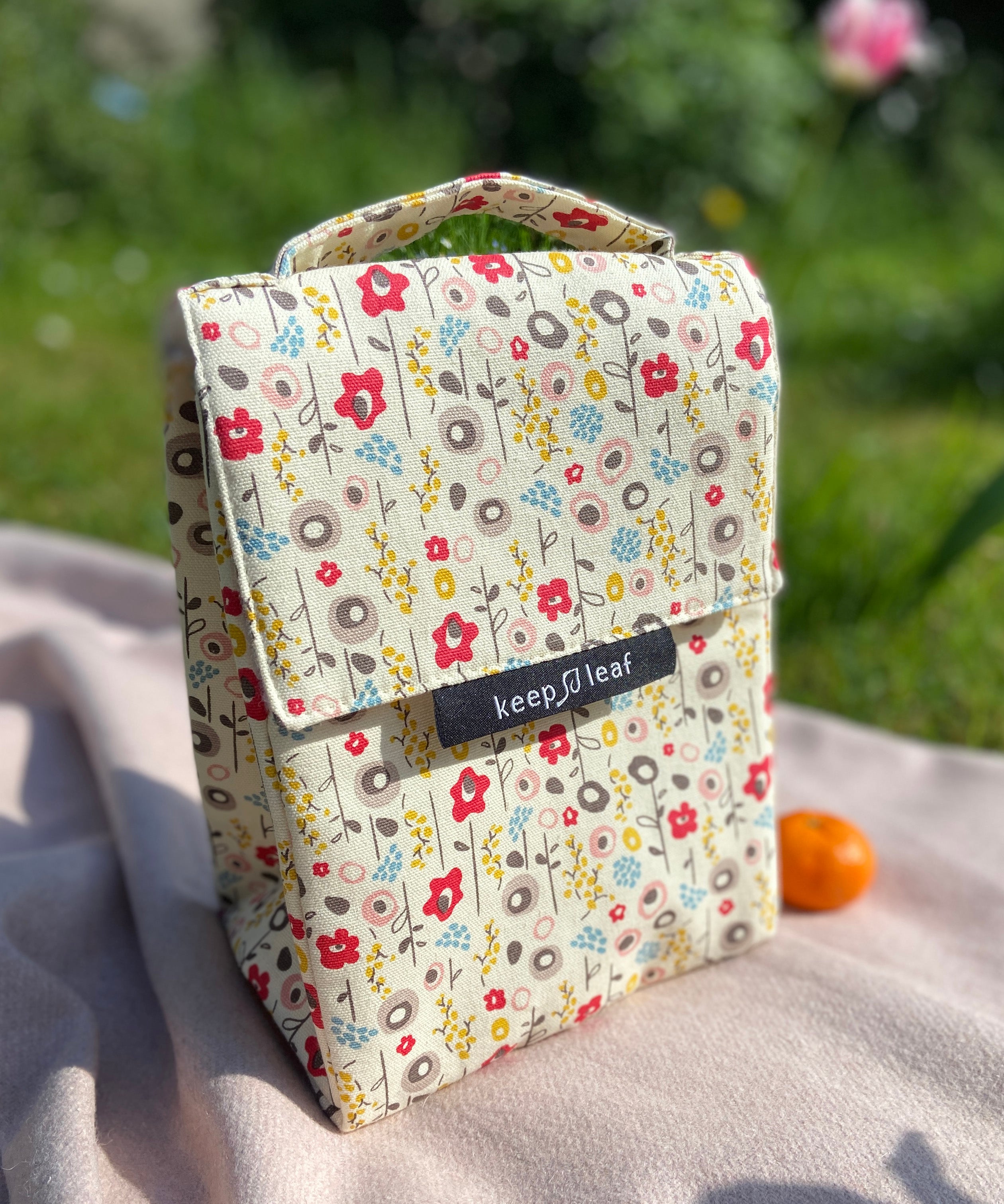 Keep Leaf insulated lunchbag in bloom design on a blanket in the garden