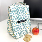 Keep Leaf insulated lunchbag in geo design on a desk next to an apple and crackers.