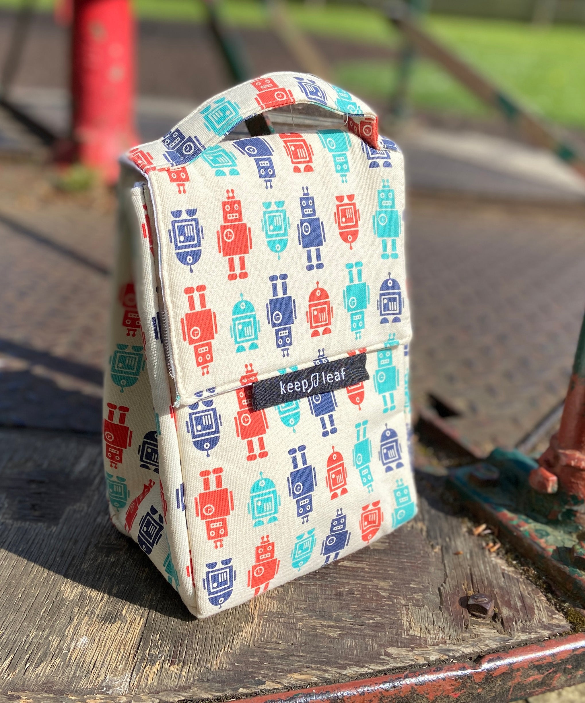 Keep Leaf insulated lunchbag in robot design standing outside on a wooden surface