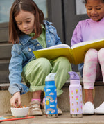 Two children sitting on a step outside, they have two Kid Kanteen 12oz Insulated Flip Seal Sport Cap Bottles in front of them. One bottle has a rainbow print, the other has an ice cream print.
