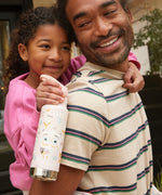 A child getting a piggy back teh child is holding an Owlet print Kid Kanteen 12oz Insulated Flip Seal Sport Cap Bottle.