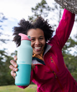 A woman hanging from a tree outside and holding the bay 16oz stainless steel reusable klean kanteen insulated rise bottle