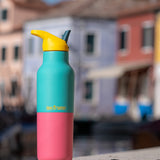 A klean Kanteen 16oz reusable stainless steel rise insulated bottle on a stone wall  showing the blue and pink kaleidoscope colour way design with the yellow flip sports lid
