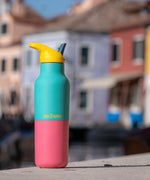 A klean Kanteen 16oz reusable stainless steel rise insulated bottle on a stone wall  showing the blue and pink kaleidoscope colour way design with the yellow flip sports lid