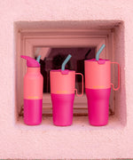 Klean Kanteen pink lemonade kaleidoscope 16oz, 26 oz and 36oz rise insulated stainless steel bottle and tumblers standing in front of a window showing the pink colour way and handle detail on the tumblers