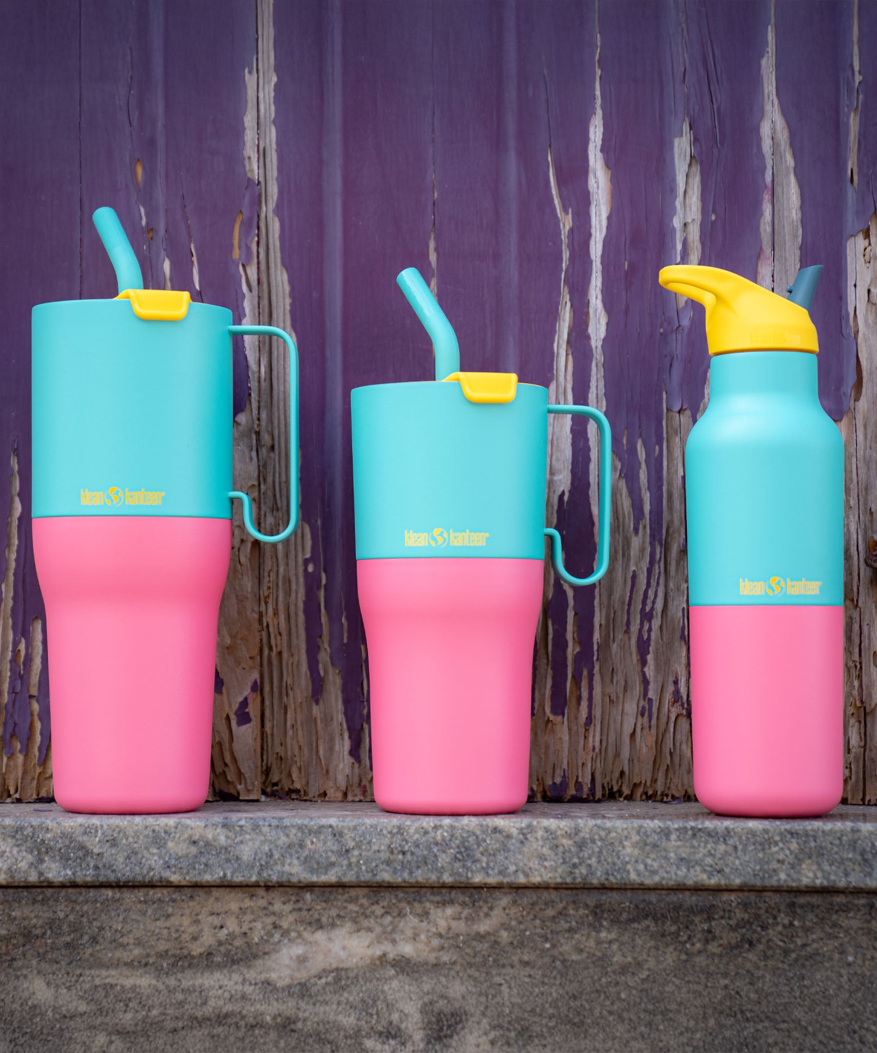 Klean Kanteen turquoise kaleidoscope 16oz, 26oz and 36oz rise insulated stainless steel bottle and tumblers on a stone surface showing the pink and turquoise colour way design and handle detail on the tumblers