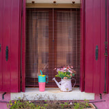 A Klean Kanteen 26oz turquoise kaleidoscope stainless steel insulated rise tumbler on a windowsill next to a watering can for scale showing the pink and turquoise colour way with a yellow flip cap. Features a turquoise handle on the side with a matching straw