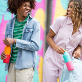 2 young adults holding the marigold and turquoise kaleidoscope 16oz Klean Kanteen insualted rise bottles by their flip sports cap showing scale and colour way designs