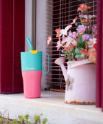 A close up of the turquoise kaleidoscope Klean Kanteen 26oz rise insulated tumbler on a windowsill  next to a watering can showing the pink and turquoise colour way design with the turquoise straw and handle detail