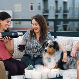 3 people and a dog sat on an outdoor sofa