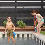 Two children in a splash pool, one is holding the Sharks in Shades Kid Kanteen 12oz Narrow Flip Seal Sport Cap Bottle the other has an insulated Rainbow print Kid Kanteen Bottle.