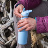 A close up of a person's hand holding a Clear Sky coloured Klean Kanteen 18oz Classic Narrow Leakproof Flip Seal Sports Cap Reusable Stainless Steel Water Bottle.