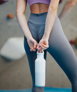 A women standing and holding the barely blue 20oz Klean Kanteen Reusable Stainless Steel Water Bottle