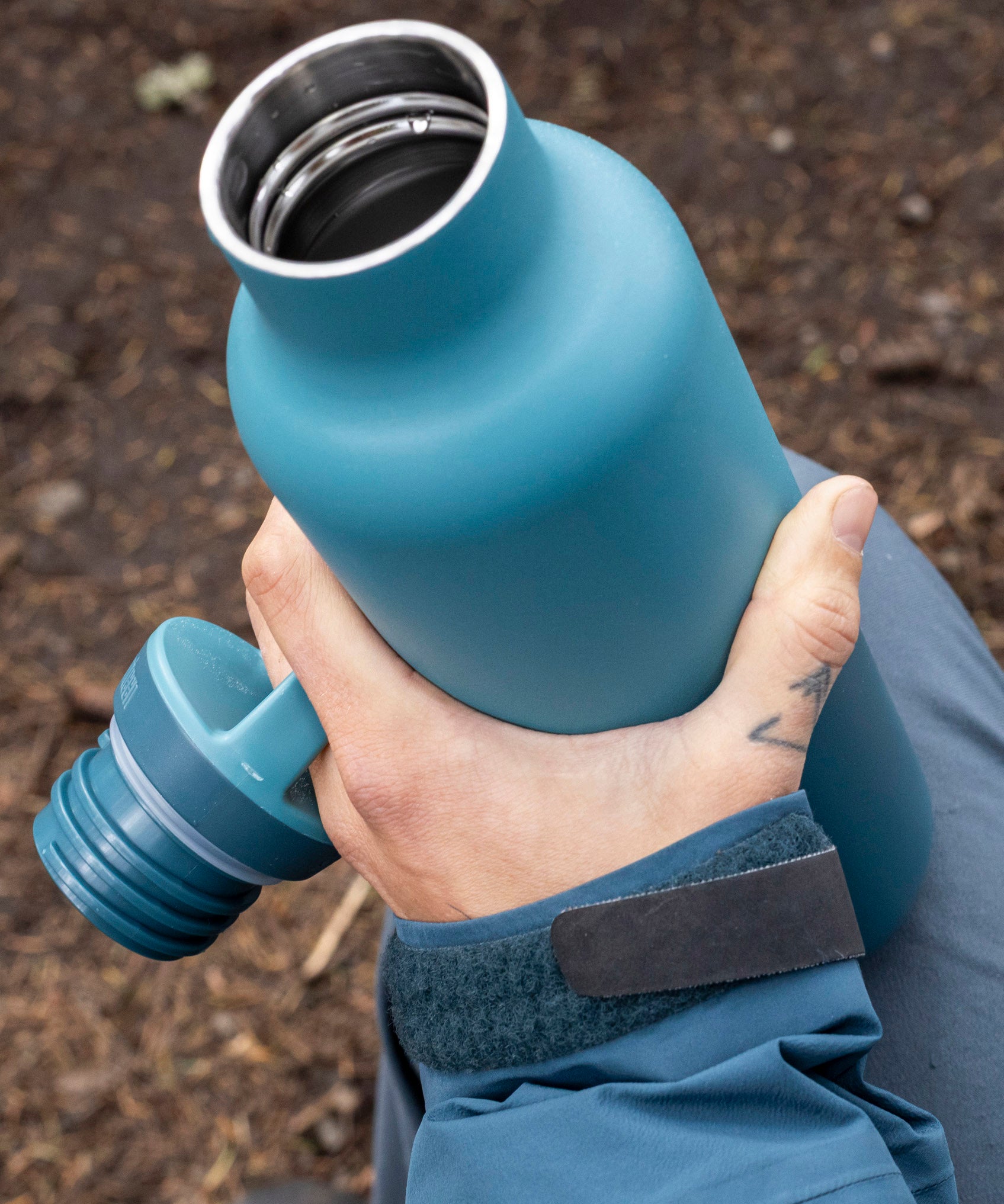 A adult hand holding the Brittany blue 20oz Klean Kanteen Reusable Stainless Steel Water Bottle with the loop cap off and showing the inside thread detail