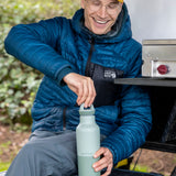 A man sitting outside and holding the iceberg 20oz rise Klean Kanteen water bottle and closing the matching loop cap on the bottle