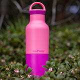 A close up of the 20oz rise classic Klean Kanteen water bottle in pink lemonade standing outside showing the contrast pink coating detail.