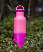 A close up of the 20oz rise classic Klean Kanteen water bottle in pink lemonade standing outside showing the contrast pink coating detail.