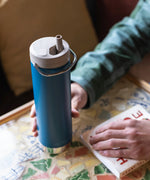 A close up of a person's hand holding a cosair blue coloured Klean Kanteen 20oz TKWide .