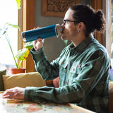 A person drinking from a corsair blue coloured Klean Kanteen 20oz TKWide .