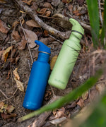 Two corsair blue and shadow lime coloured Klean Kanteen 27oz Classic Narrow Leakproof Flip Seal Sports Cap Reusable Stainless Steel Water Bottle laying on the ground.