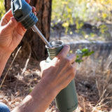 A close up of a person opening the lid of a Sea Spray green coloured Klean Kanteen 27oz Classic Narrow Flip Seal Sports Cap Reusable Stainless Steel Water Bottle.