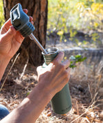 A close up of a person opening the lid of a Sea Spray green coloured Klean Kanteen 27oz Classic Narrow Flip Seal Sports Cap Reusable Stainless Steel Water Bottle.