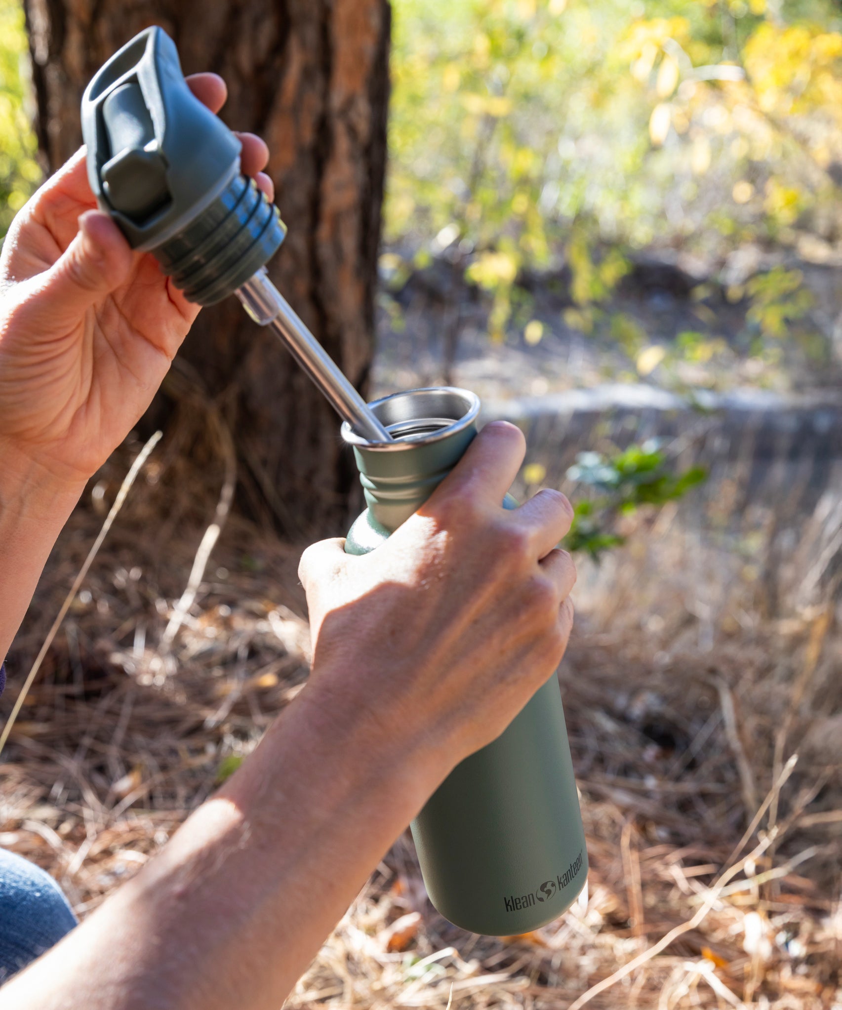 A close up of a person opening the lid of a Sea Spray green coloured Klean Kanteen 27oz Classic Narrow Flip Seal Sports Cap Reusable Stainless Steel Water Bottle.