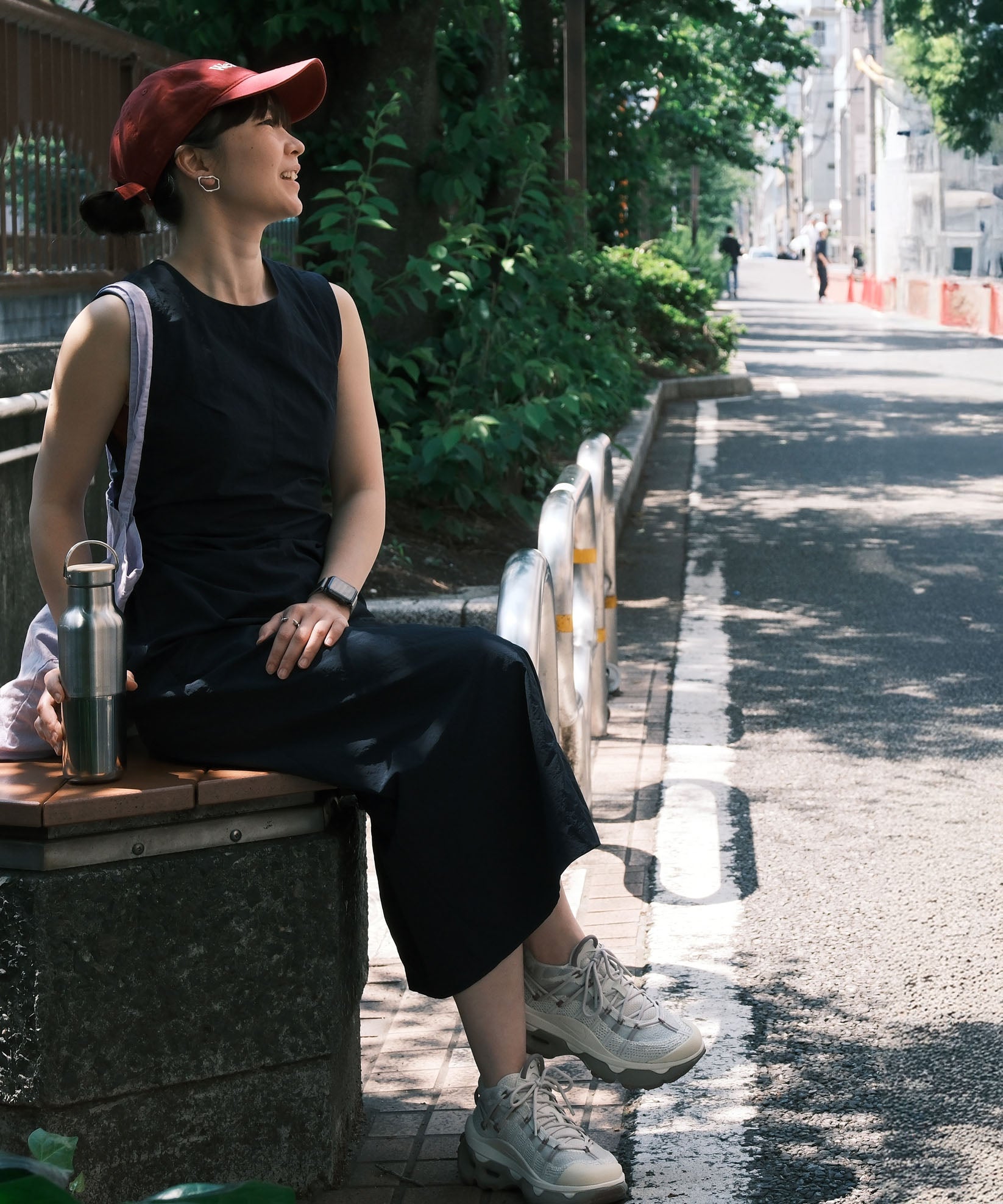 A woman sitting on a bench and holding the Klean Kanteen rise stainless steel bottle with bamboo lid. Bottle available at Babipur.