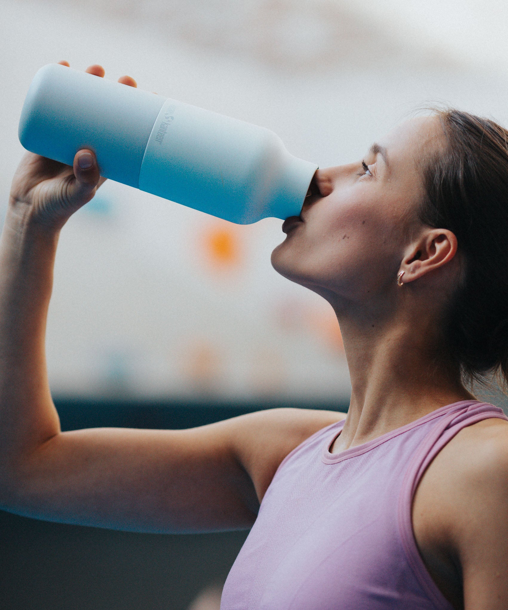 A woman drinking from the the 20oz barely blue stainless steel reusable Klean Kanteen bottle