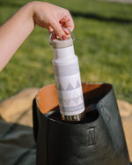 Close up of womans hand pulling a Klean Kanteen stainless steel insulated bottle from a handbag