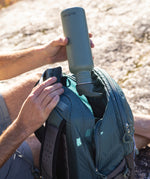 A person is putting the Klean Kanteen bottle with a flip seal sports cap in their bag, with the bottle upside down to demonstrate how it's a leakproof cap.