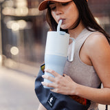 A person holding the icy blue colour Klean Kanteen Limited Edition 36oz Rise Tumbler whilst sipping through the silicone tipped straw