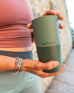 Close up of a woman holding a Klean Kanteen stainless steel tumbler in the Ocean Spray green colour
