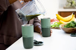 Close up of person pouring a green smoothie from a jug into a Klean Kanteen green stainless steel 16oz tumbler