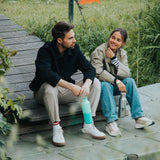 2 adults sitting down and holding the Klean Kanteen reflect stainless steel rise bottles by the handles on the loop cap